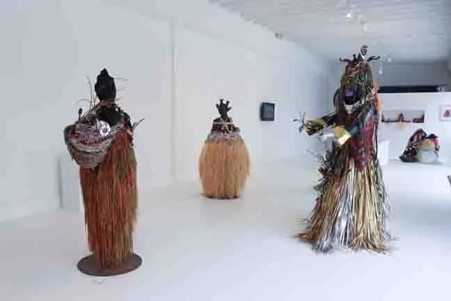 Installation view of litany: wrapped and adorned figurative sculptures in a white gallery.